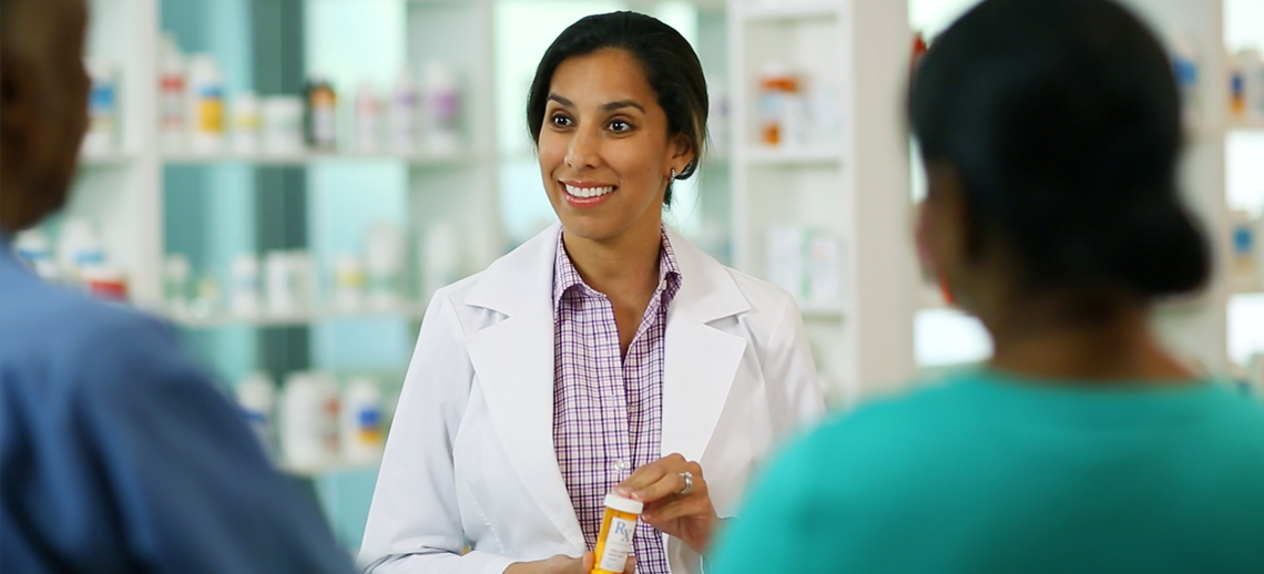 Pharmacist reviewing prescriptions with customers